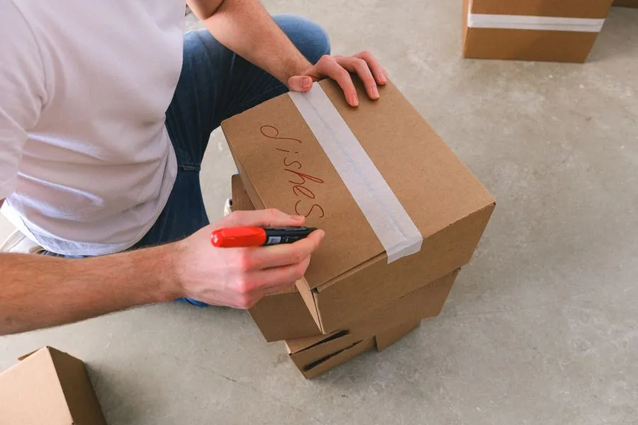Persona etiquetando una caja de cartón para la mudanza